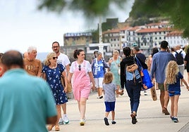 Varias personas pasean junto a la playa de La Concha de San Sebastián este verano.