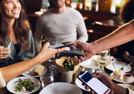 Una persona paga con tarjeta a través del móvil en un restaurante.