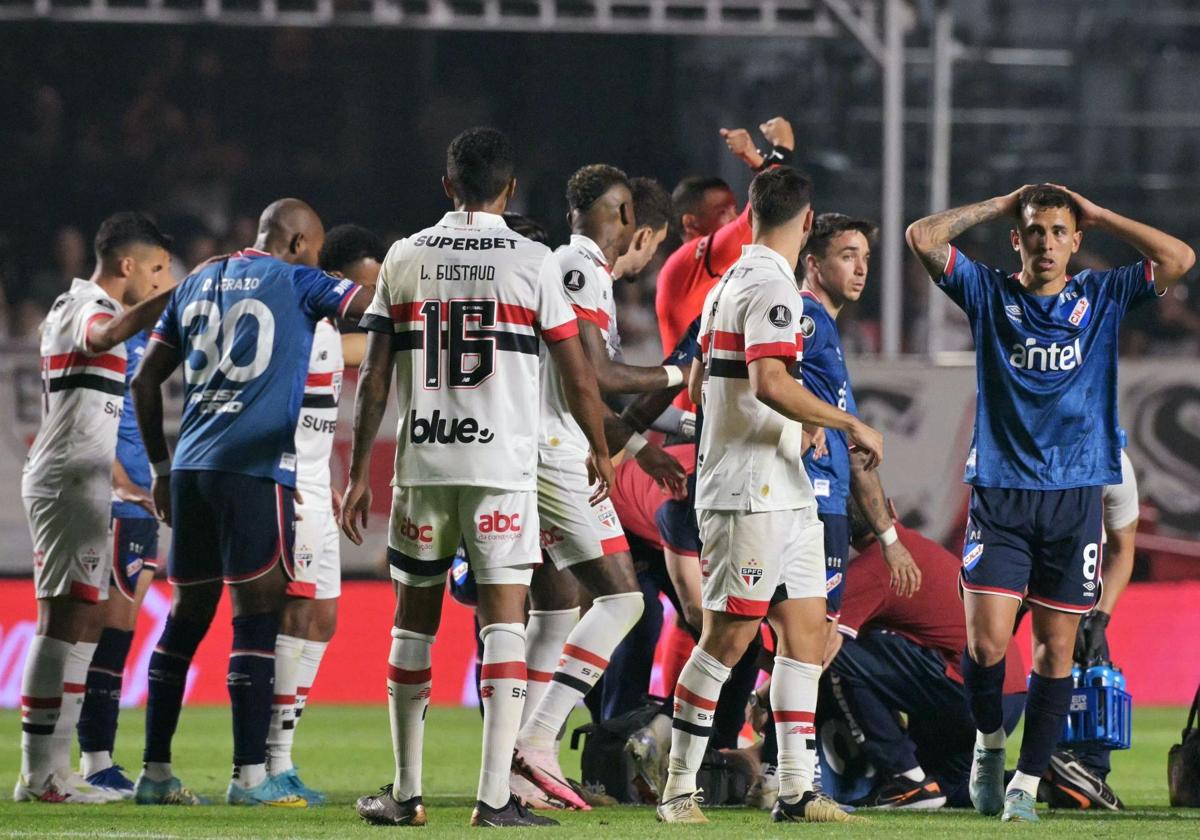 Jugadores de Nacional y Sao Paolo se echan las manos a la cabeza tras desplomarse Juan Izquierdo en el partido de la Copa Libertadores.