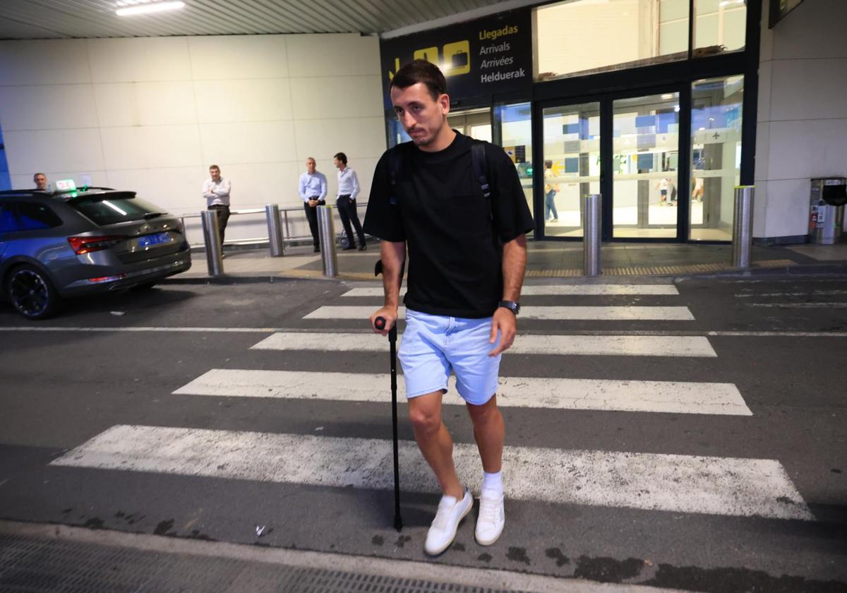 Mikel Oyarzabal, con gesto serio, camina con una muleta y el tobillo vendado tras aterrizar a última hora de la tarde de este viernes en el aeropuerto de Hondarribia.