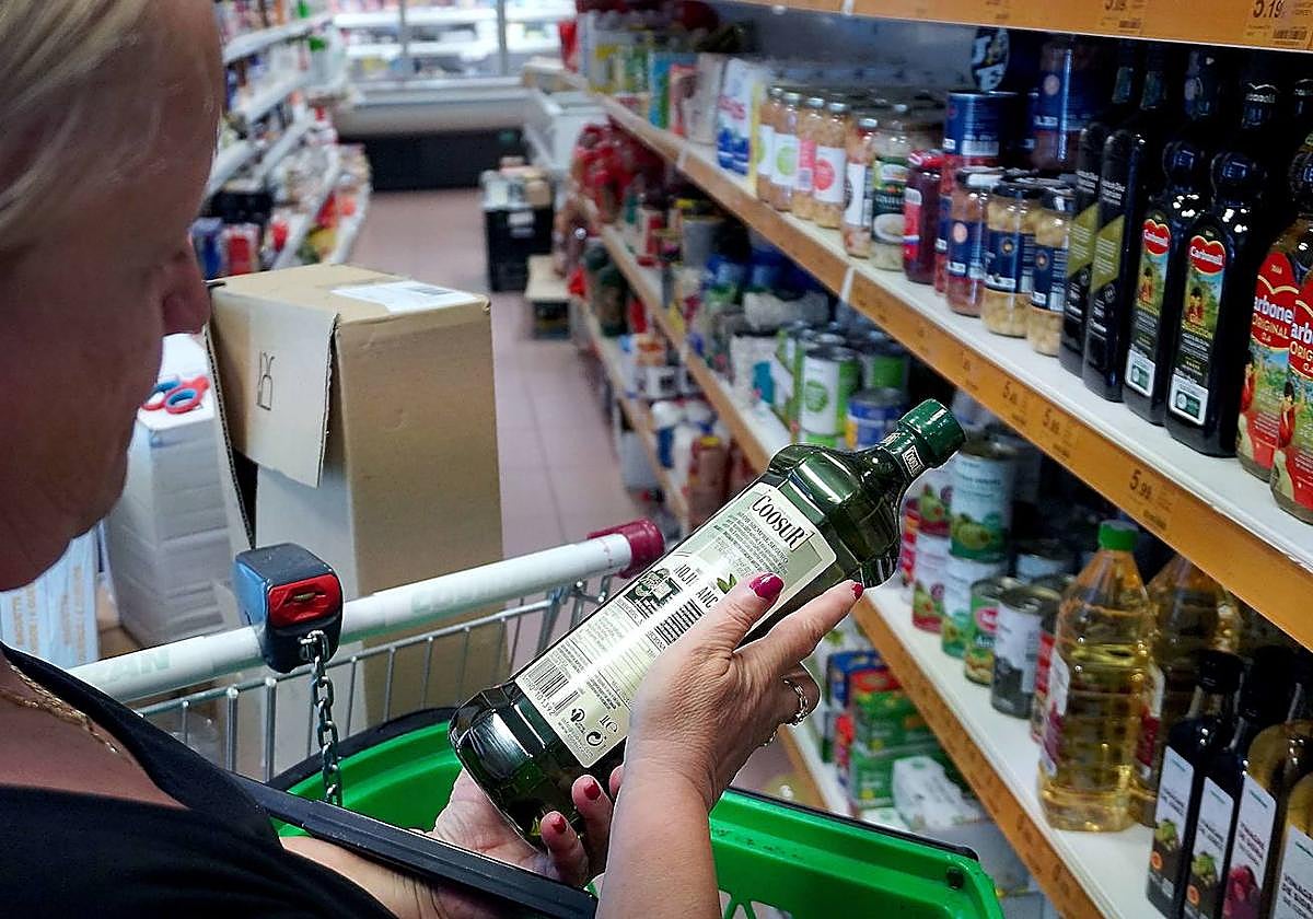 Una mujer observa una botella de aceite en un supermercado.