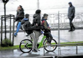 Tres jóvenes circulan en una bicicleta por La Concha, algo totalmente prohibido.