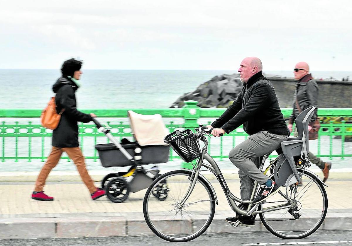 Un hombre circula con su bicicleta por el puente de Zurriola.