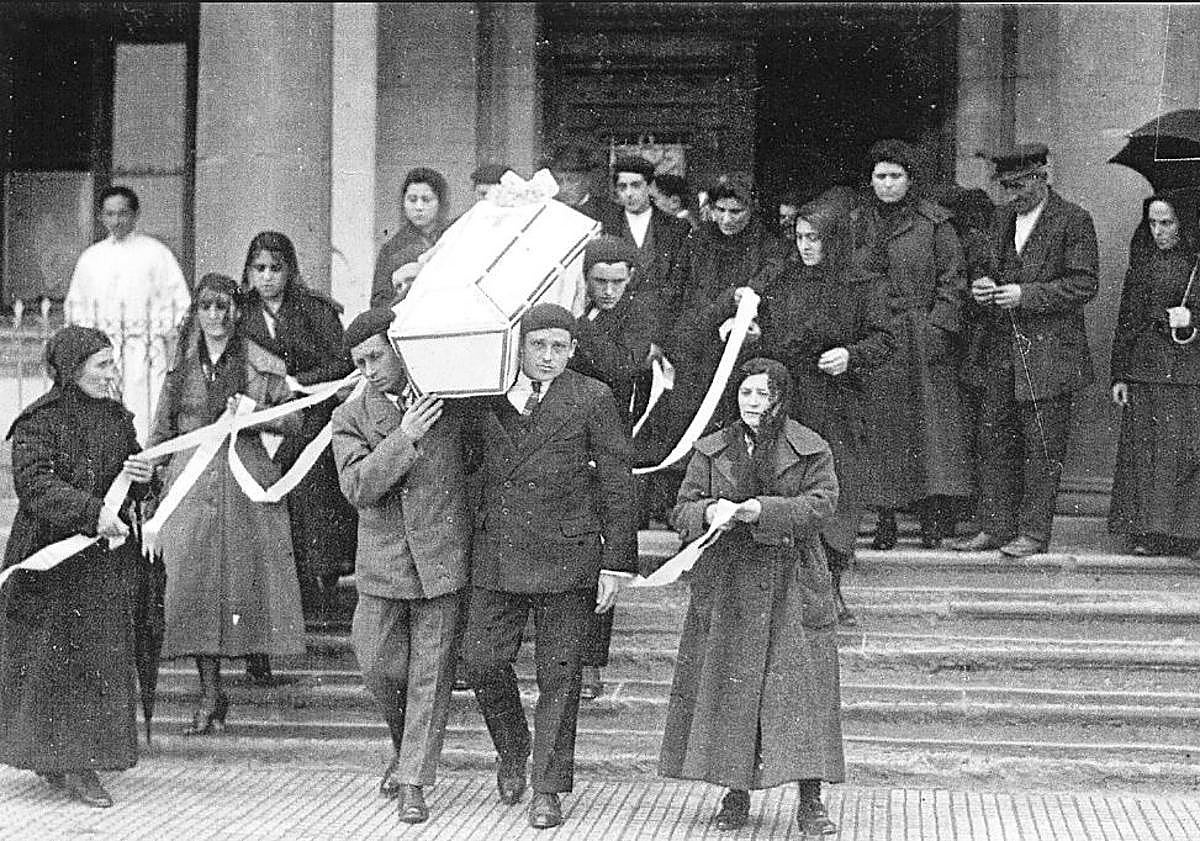 Imagen principal - Traslado de un féretro de una vivienda de Donostia al cementerio de Polloe. Un operario lleva a hombros el ataúd de un niño, y comitiva fúnebre en Arrasate.