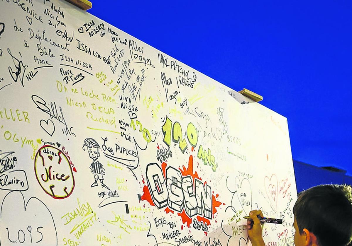 Unos niños firman en un mural por el 120 aniversario del Niza.