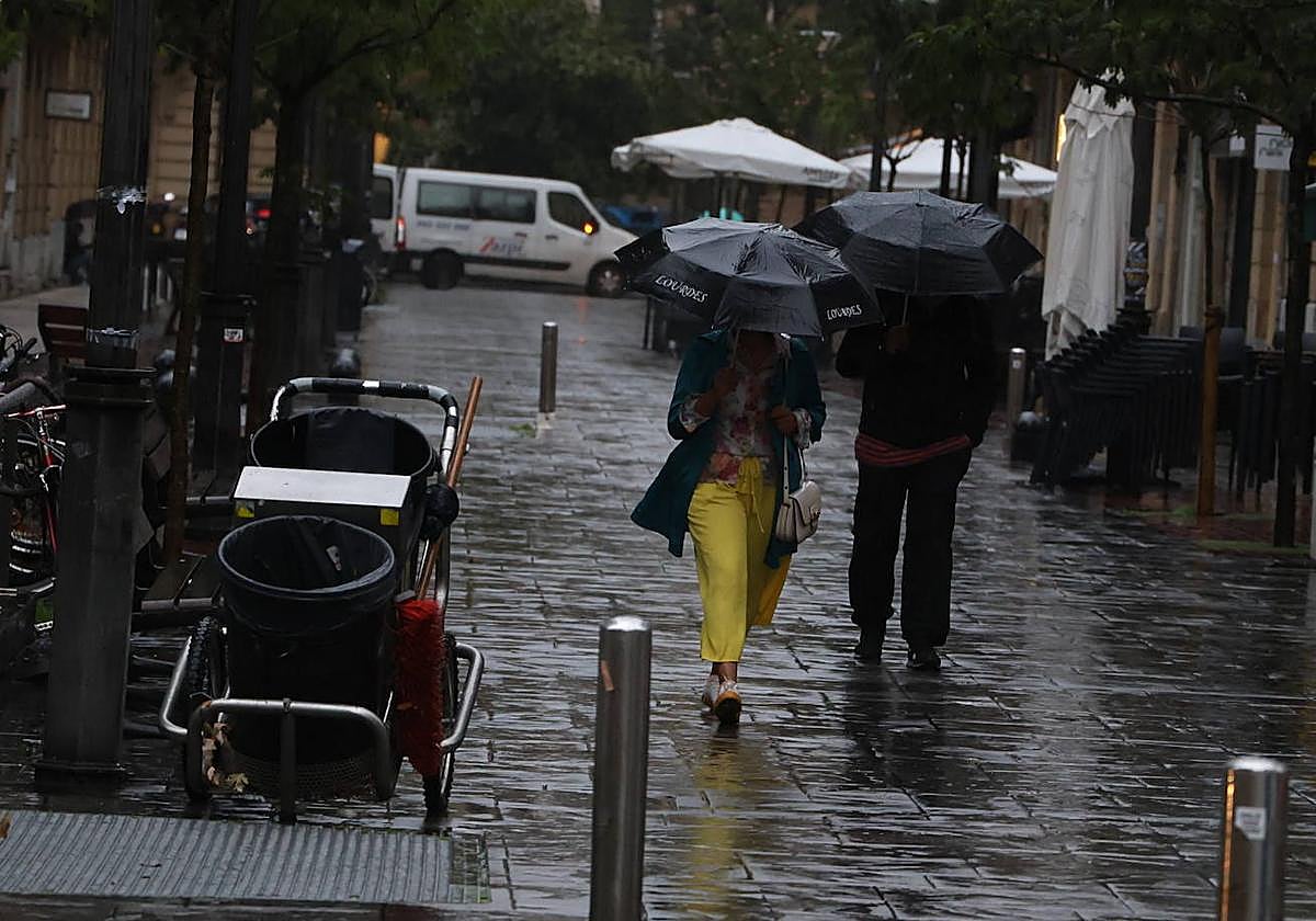 Una pareja pasea bajo la lluvia en una calle del centro de San Sebastián a primera hora de esta mañana.