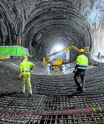 Imagen secundaria 2 - Revestimiento de la galería con hormigon, montaje de las vías y operarios pasando por el entramado de la contravóbeda de la estación Centro.