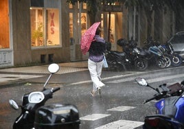 Una mujer se refugia de la lluvia bajo un paraguas en Donostia.
