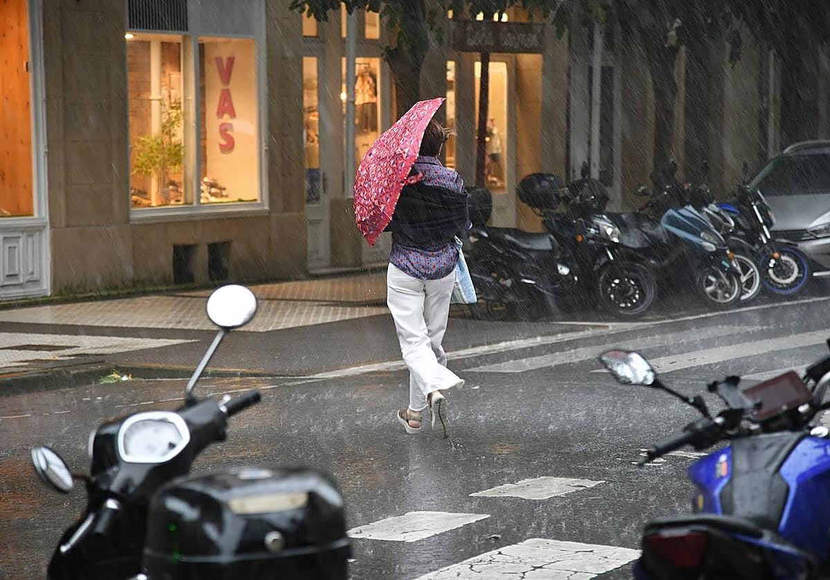 Una mujer se refugia de la lluvia bajo un paraguas en Donostia.