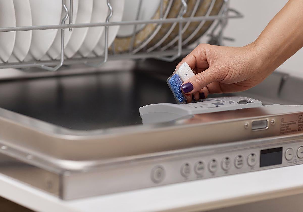 Una persona introduce una pastillas al lavavajillas.