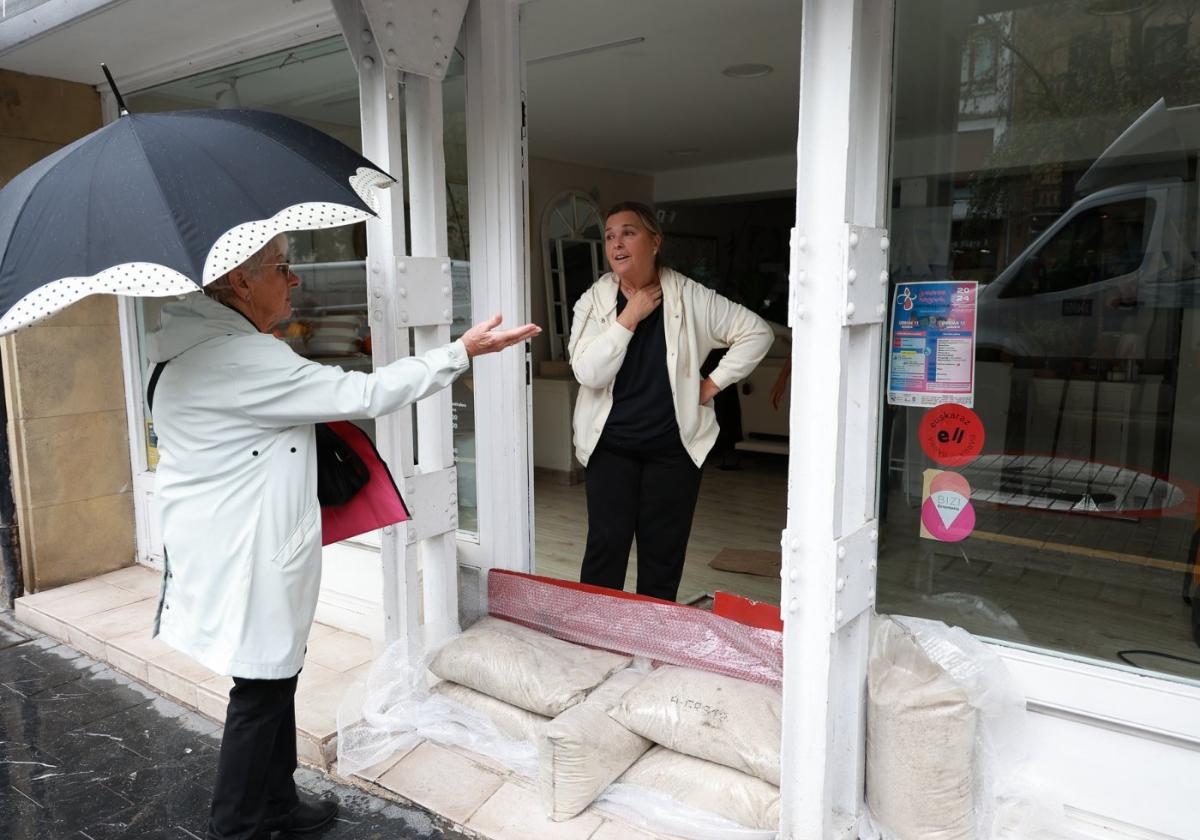 Aintzane comenta con una vecina cómo entró el agua en la tienda en la tarde del jueves.