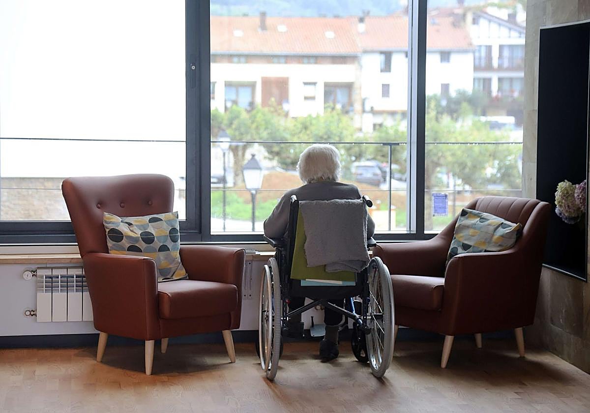 Una mujer en silla de ruedas observa desde la ventana de una residencia en Usurbil.