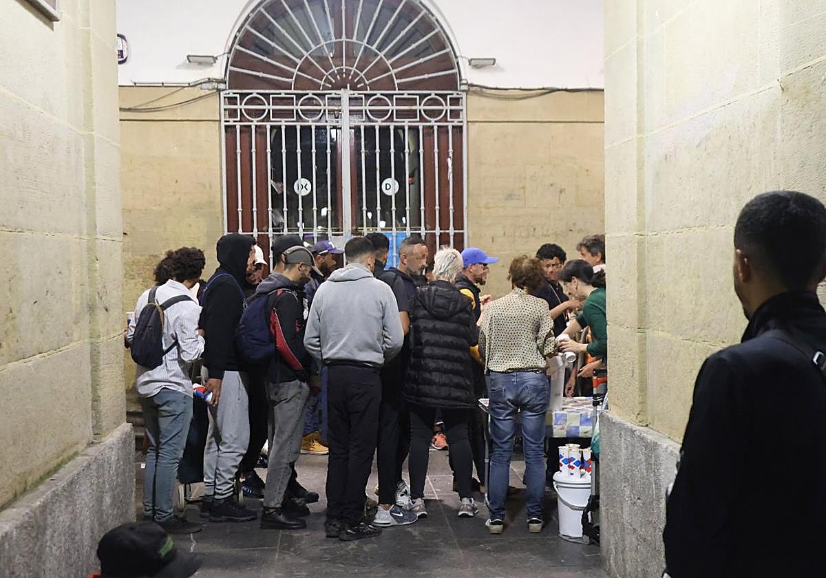 Decenas de sintecho seagolpan bajo losarkupes de la bibliotecade la plaza de laConstitución para recibirsu cena.
