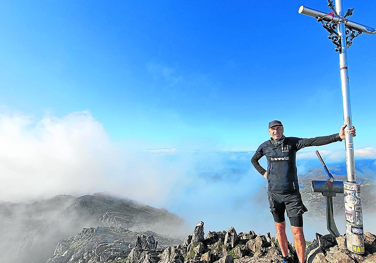 Carlos Morán sujeta la cruz de Aizkorri en la cima a la que ha subido centenares de ocasiones.