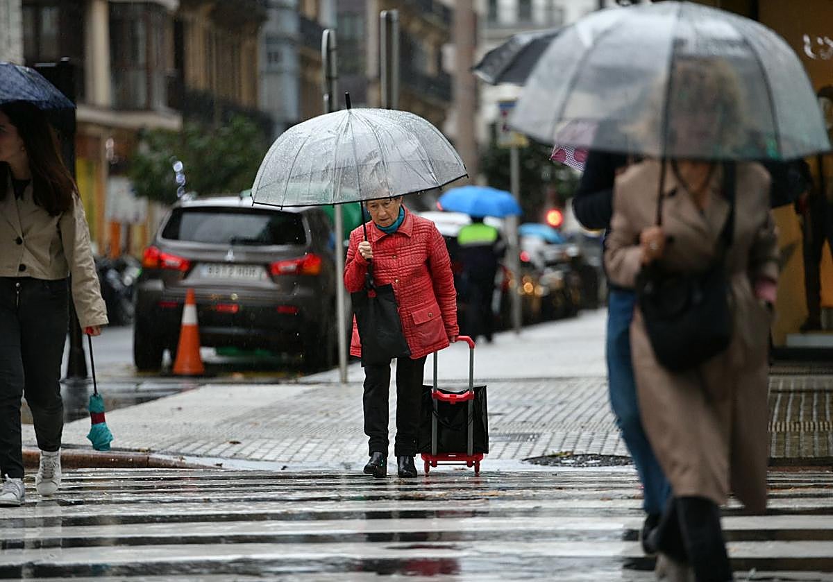 Varias personas se refugian de la lluvia bajo el paraguas en Donostia.