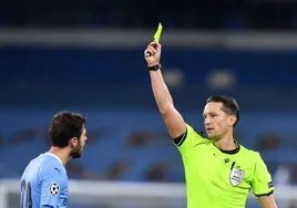 El árbitro letón Andris Treimanis muestra una tarjeta amarilla a Bernardo Silva, del Manchester City, durante el partido de Champions League ante el Porto en el Etihad Stadium en 2021