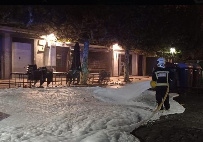 Un bombero echa espuma sobre la zona en la que se quemaron los contenedores.