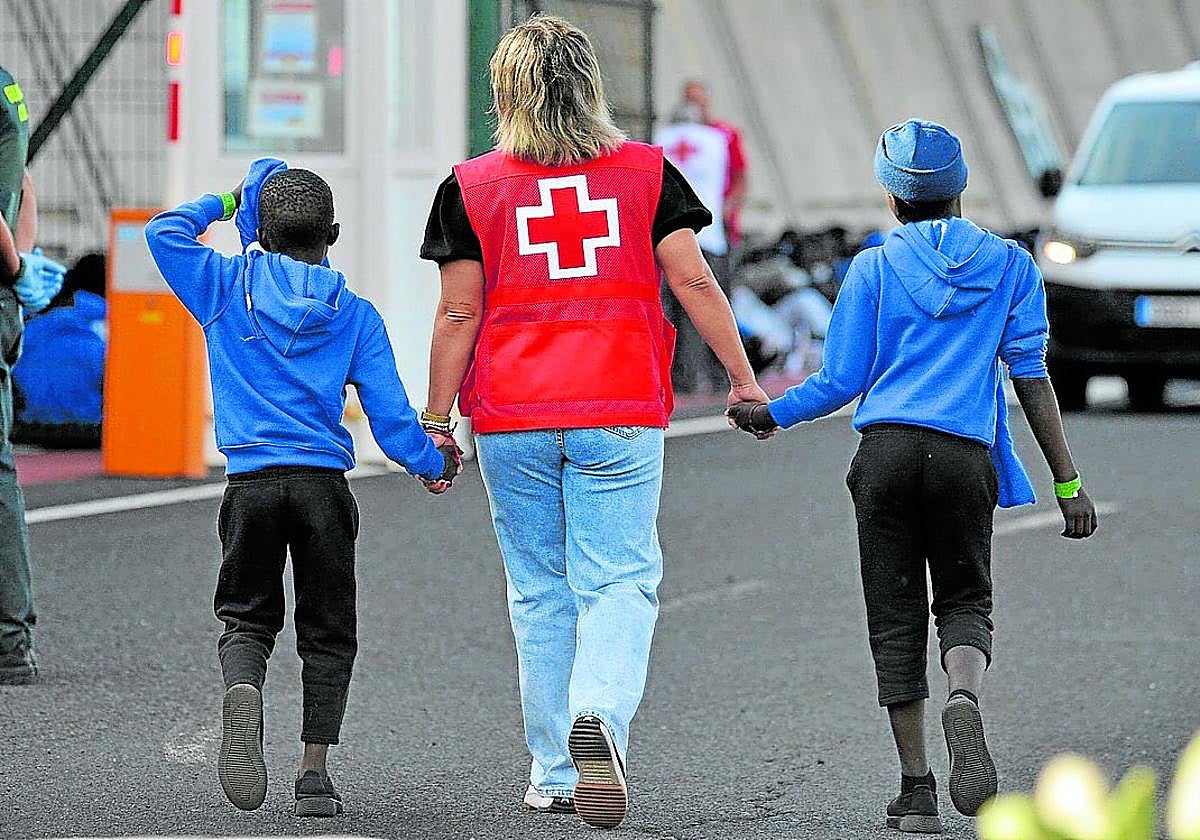 Una voluntaria atiende a dos menores extranjeros no acompañados recién llegados a Canarias.