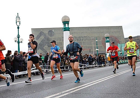 Los corredores de la behobia a su paso por el puente Kursaal bajo el cielo cubierto.