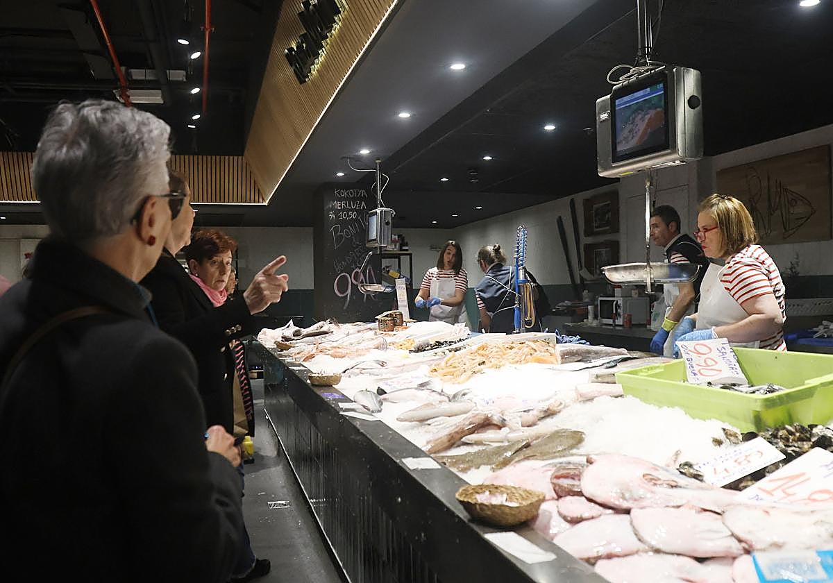 Clientes a la espera su turno en uno de los puestos de pescadería del mercado San Martín en Donostia, a donde muchos ya se acercan para hacer las compras navideñas.