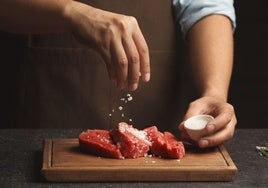 Un cocinero prepara varias raciones de carne.