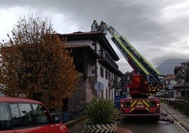 Bomberos en el tejado incendiado.