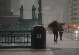 Varios viandantes se protegen de la lluvia esta mañana en Donostia.