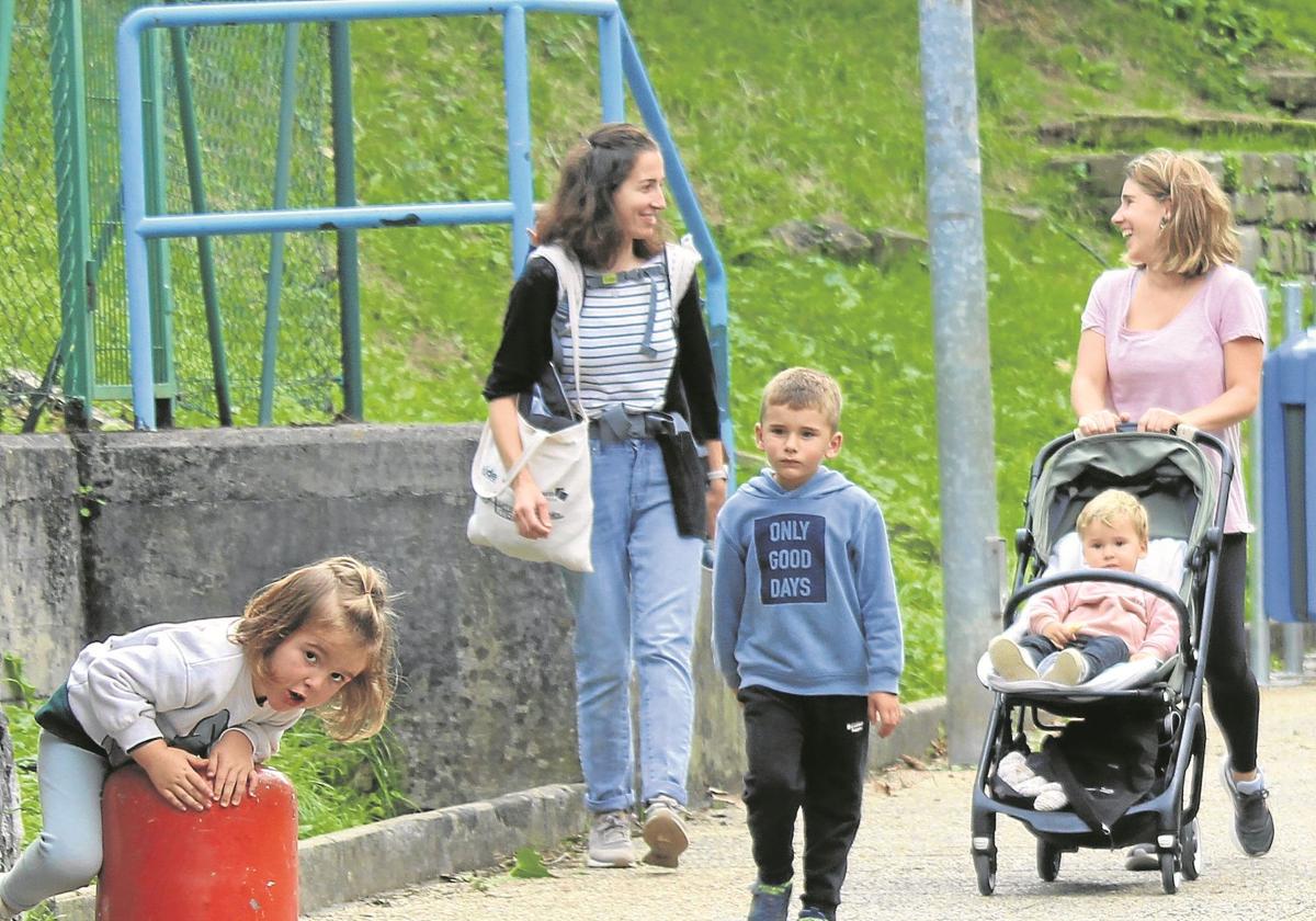 Dos jóvenes caminan junto a tres niños por Zestoa.