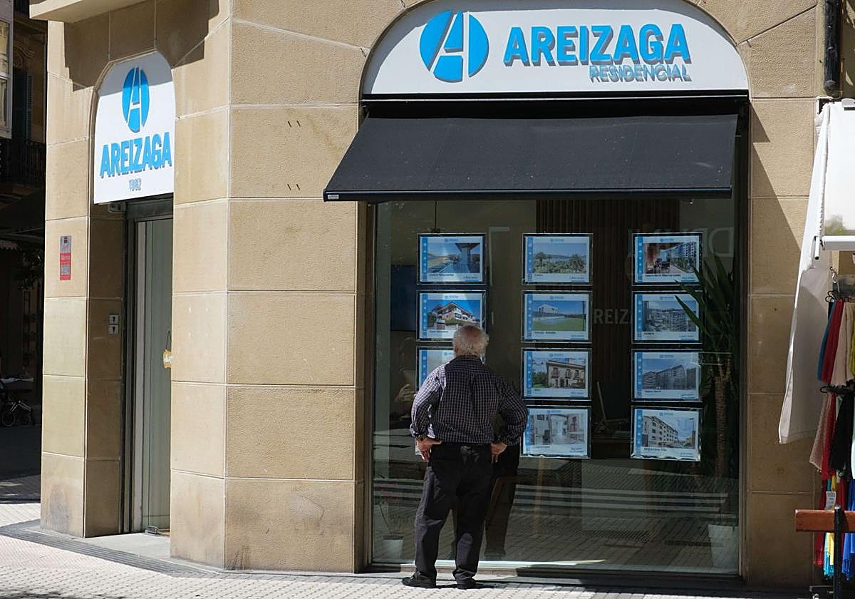Una mujer mira un escaparate de una inmobiliaria en Donostia.