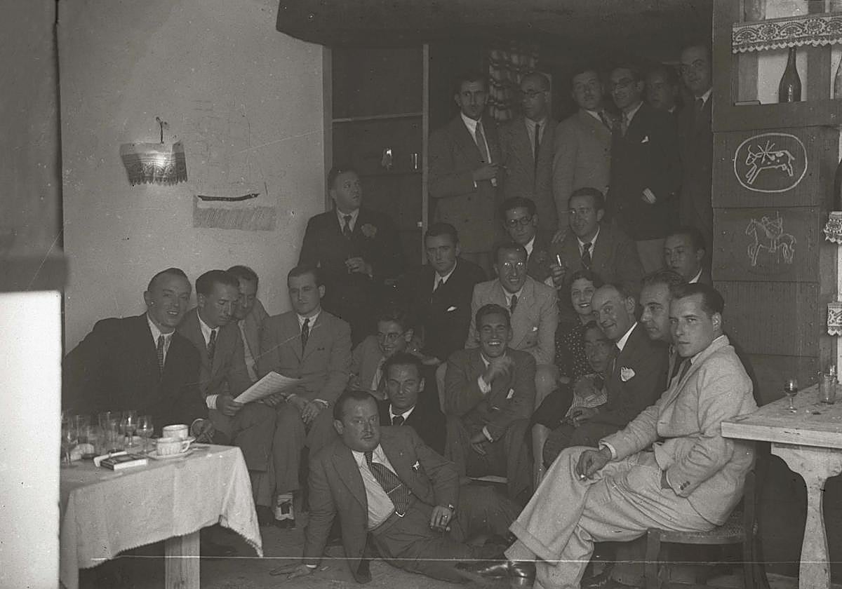 Cena inaugural de la sociedad GU en 1934, con el fotógrafo Pascual Marín, los pintores Olasagasti, Cabanas y Kaperotxipi, Julián de Tellaeche, Carlos Landi, Bautista Juanena, Miguel y Juan Pablo Logendio, Eduardo Lagarde, Ernesto Giménez Caballero, Miss Nancy, Rafael Sánchez Mazas y el arquitecto José Manuel Aizpurua, entre otros.