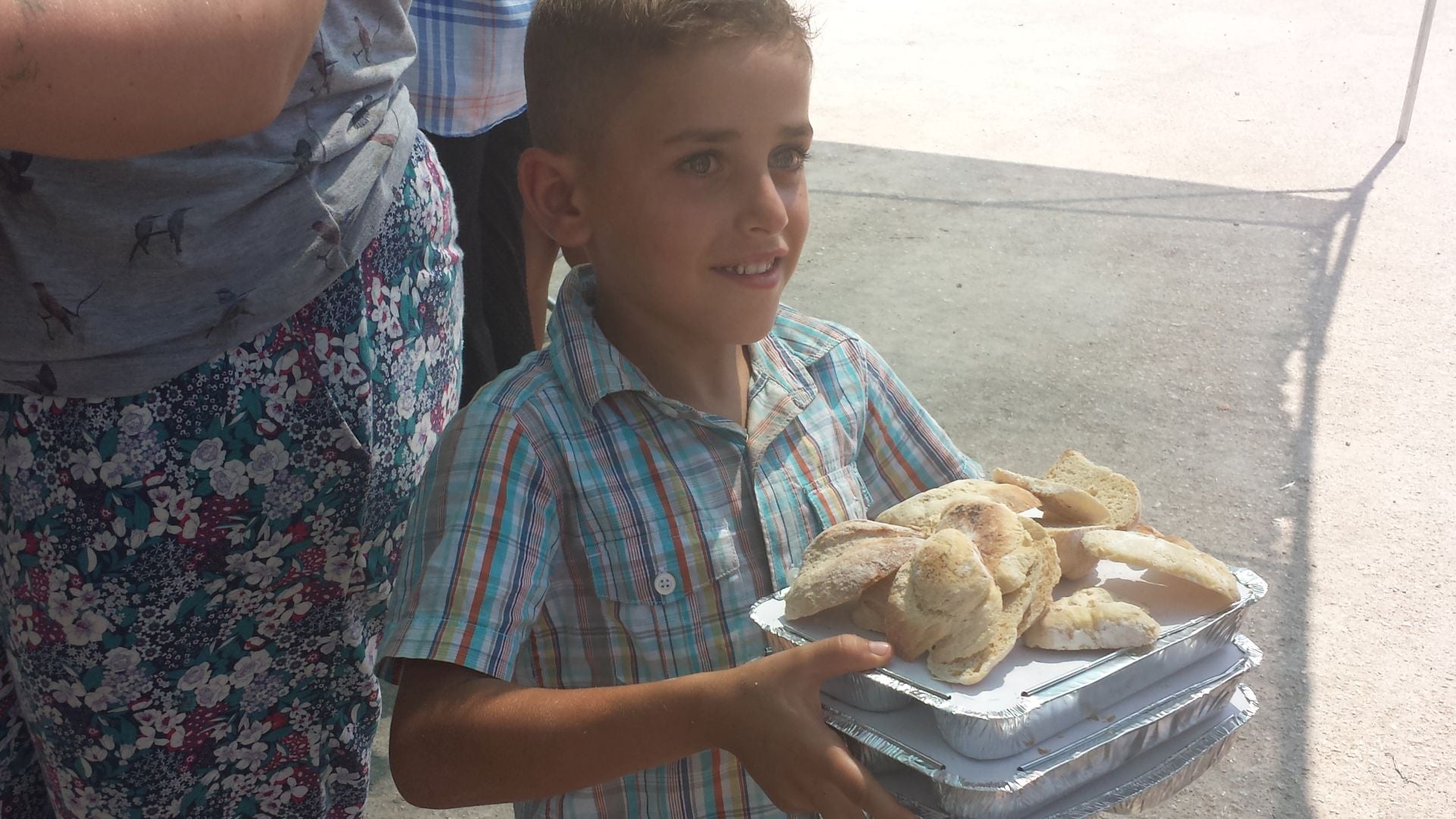 Imagen secundaria 2 - Arriba, los cocineros de Zaporeak que cada día se encargan de la alimentación. Debajo, refugiados colaborando en el reparto y debajo un niño con su ración.