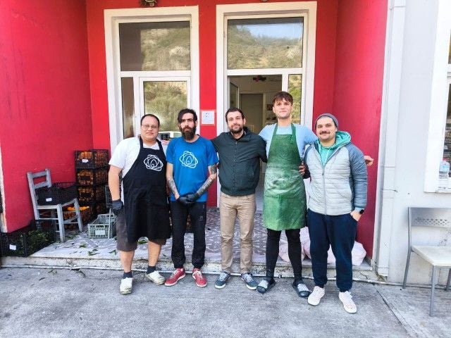 Imagen principal - Arriba, los cocineros de Zaporeak que cada día se encargan de la alimentación. Debajo, refugiados colaborando en el reparto y debajo un niño con su ración.