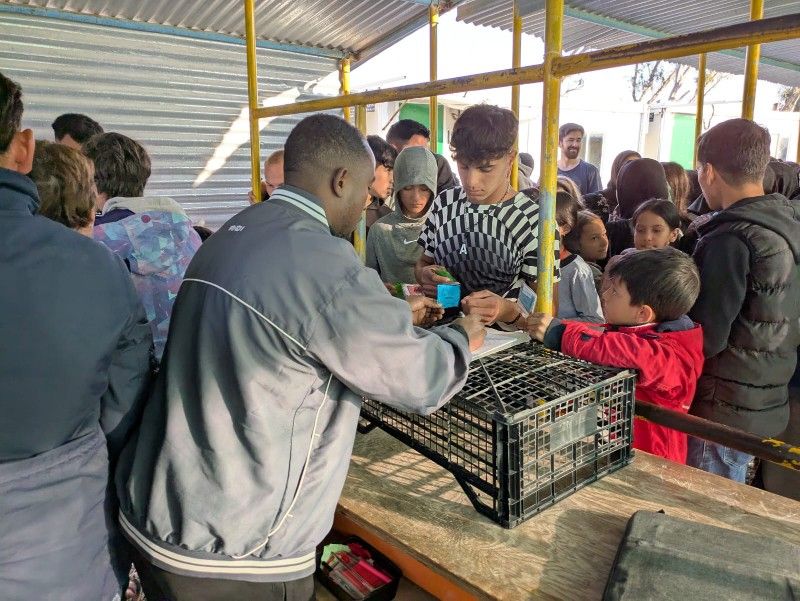 Imagen secundaria 1 - Arriba, los cocineros de Zaporeak que cada día se encargan de la alimentación. Debajo, refugiados colaborando en el reparto y debajo un niño con su ración.