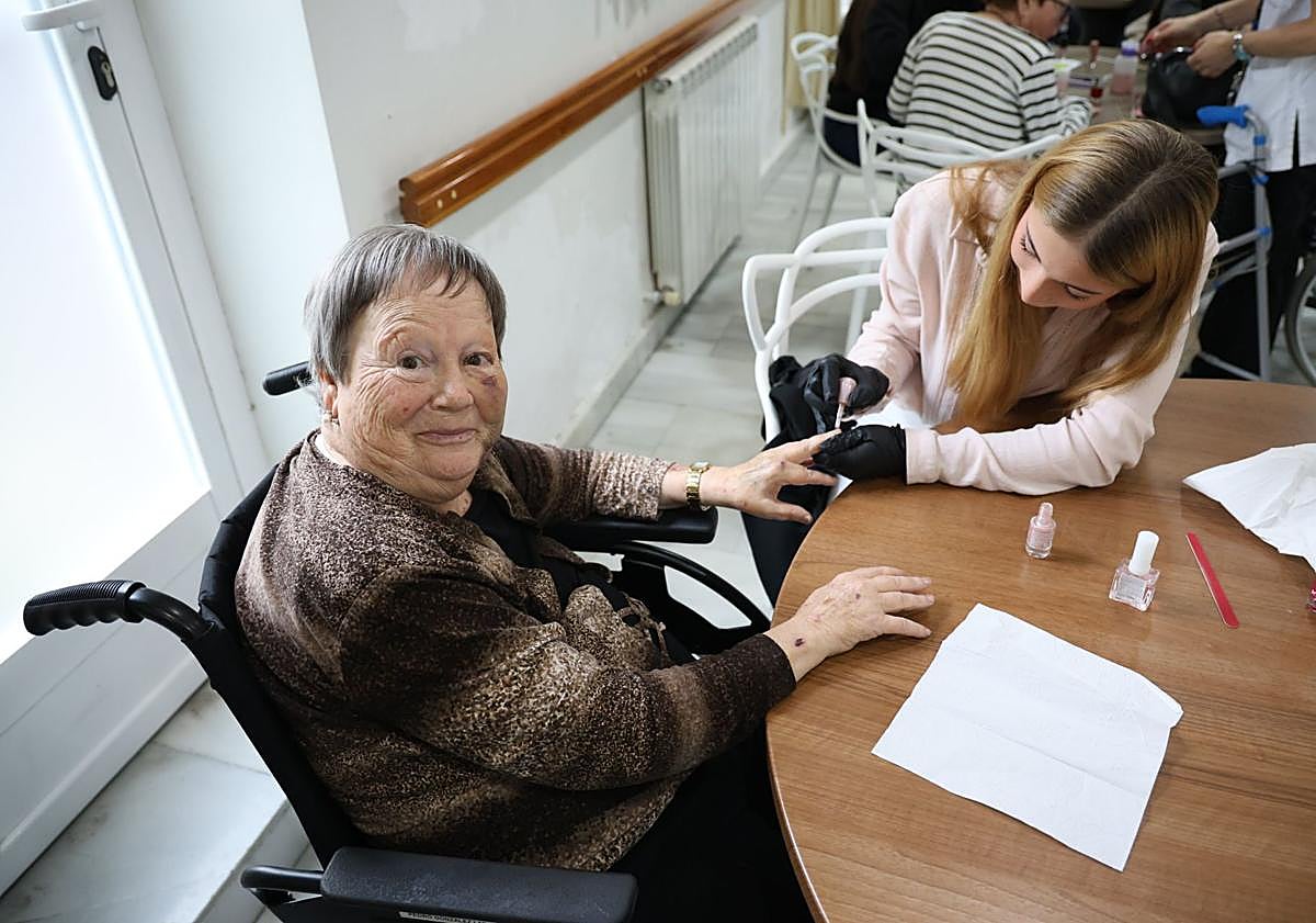 Imagen principal - Ona Pérez, de 16 años, le pinta las uñas de color rosa a Josefina Cano; Conchi enseña la manicura y las uñas que una de las alumnas le pintó en color rojo; y Naia le da un cariñoso beso a Basil.