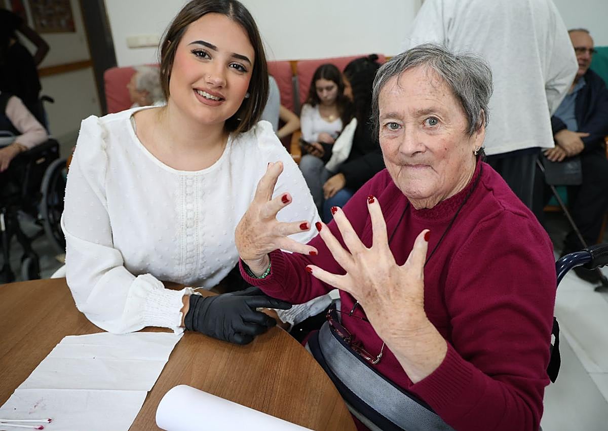 Imagen secundaria 1 - Ona Pérez, de 16 años, le pinta las uñas de color rosa a Josefina Cano; Conchi enseña la manicura y las uñas que una de las alumnas le pintó en color rojo; y Naia le da un cariñoso beso a Basil.