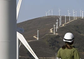 Una trabajadora observa la hilera de molinos de viento en Elguea-Urkilla, entre Araba y Gipuzkoa.