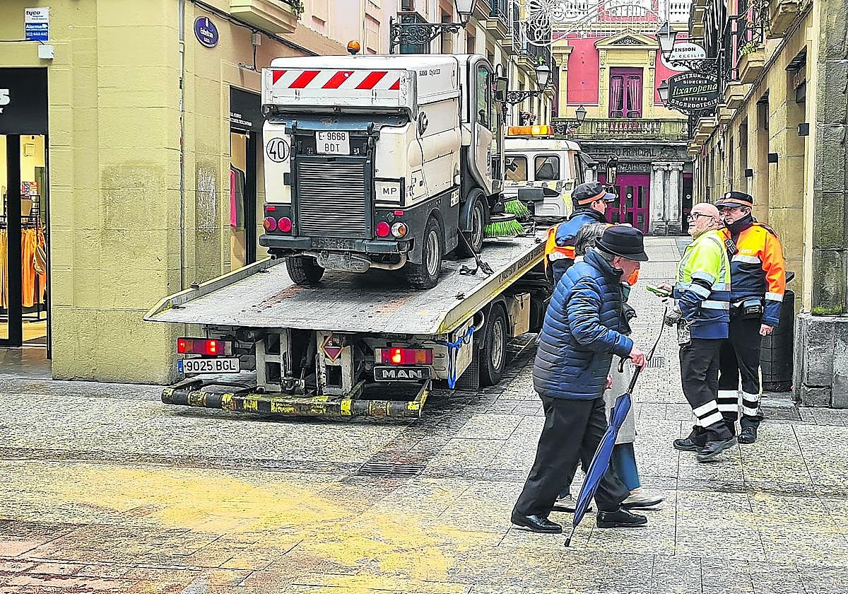 La barredora averiada es remolcada por una grúa.