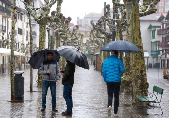 Varias personas caminan bajo el paraguas por la calle San Pedro de Hondarribia.