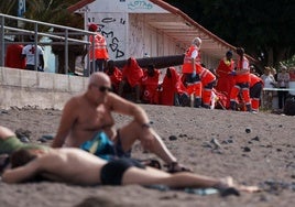 Un grupo de inmigrantes descansan en la playa de Las Galletas, en el sur de Tenerife, a la que arribaron por sus propios medios, mientras son atendidos por personal de Cruz Roja tras llegar a bordo del primer cayuco que ha alcanzado Canarias en el recién estrenado 2025 con 60 personas, dos de ellas fallecidas.