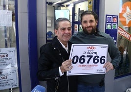 Mikel Garmendia, a la derecha, posa con su padre junto al número vendido en su administración y que ha sido agraciado con un segundo premio.