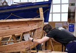 Un aprendiz trabaja en la construcción de una embarcación.