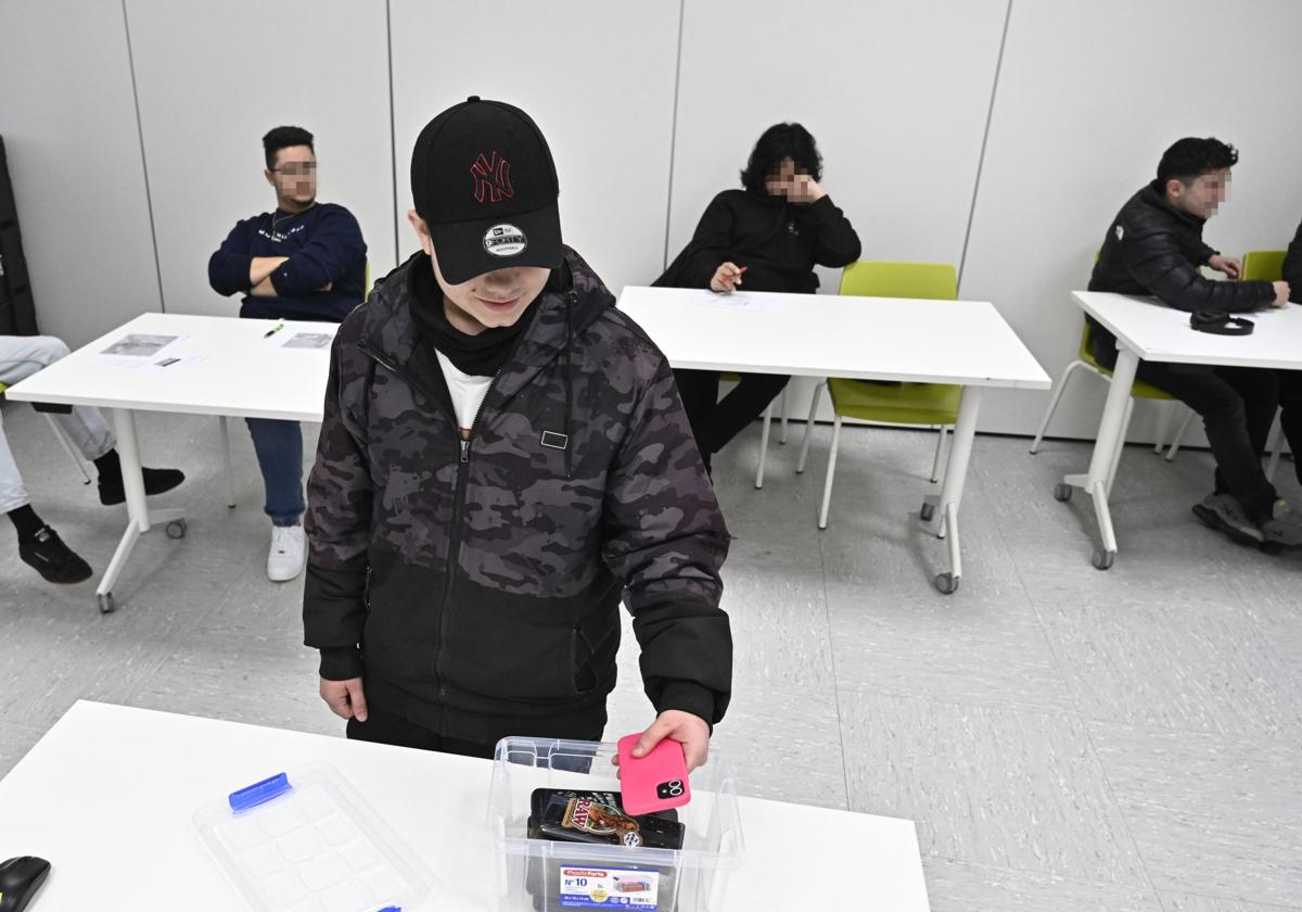 Un alumno deposita su teléfono móvil en la caja antes de arrancar la clase.