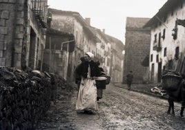 Bucólica estampa. Una mujer transita por lacalle trasera de la iglesia de Urretxu en unaimagen anterior a 1900.