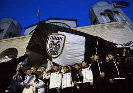 Jóvenes del PAOK ondean la bandera con el escudo del club ante la iglesia Ieros Naos Panagias Dexias, en Salónica.