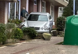 El Mercedes detenido en la entrada de un portal en Berio después de circular por la acera y llevarse por delante varias macetas.