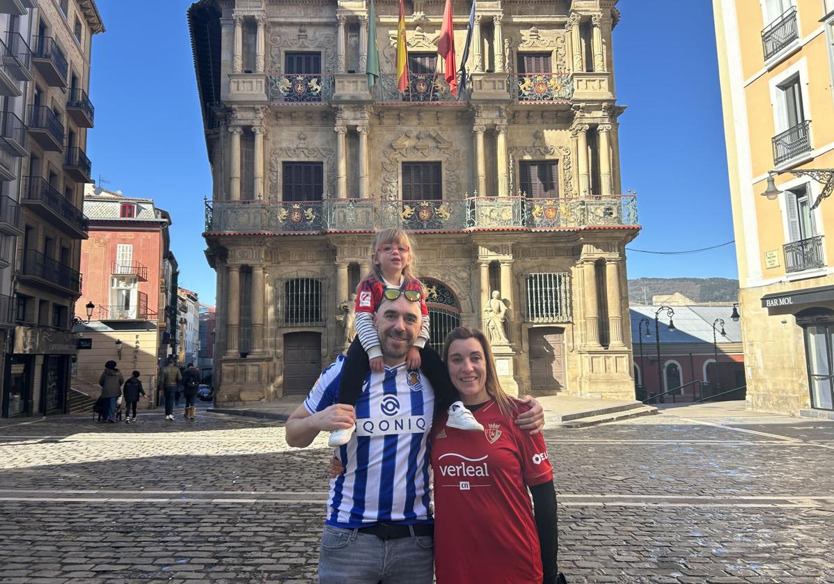 Una familia txuri-urdin y rojilla posa en la plaza del Ayuntamiento de Pamplona.