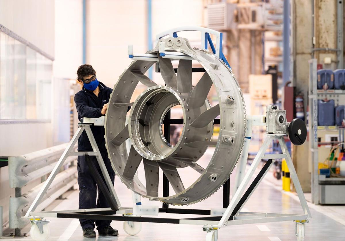 Un trabajador de ITP Aero, con la parte de un motor de un avión.