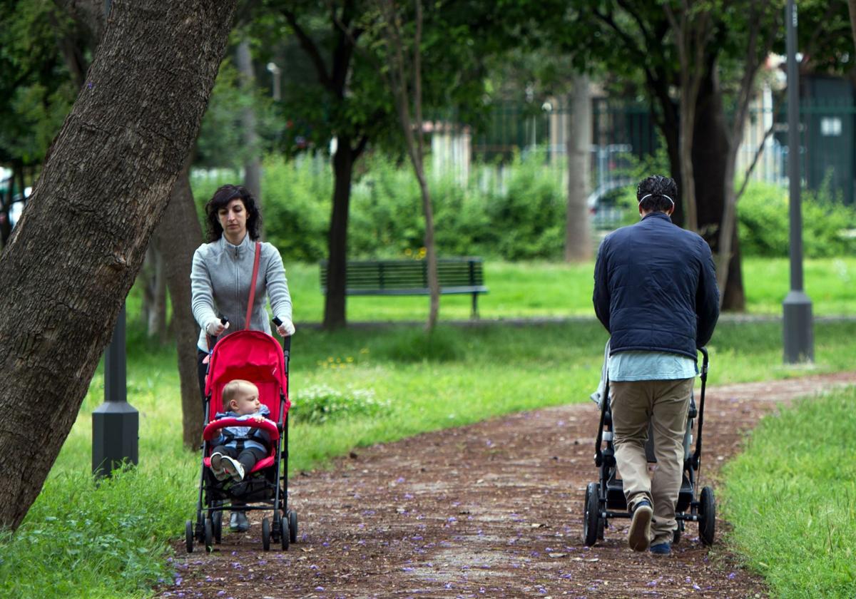 Un hombre y una mujer pasean con sus hijos por el parque.