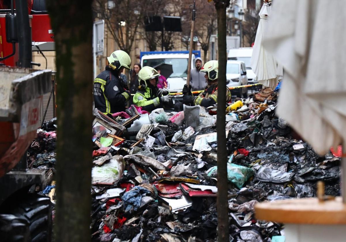 Los bomberos en labores de limpieza del piso afectado por el incendio.