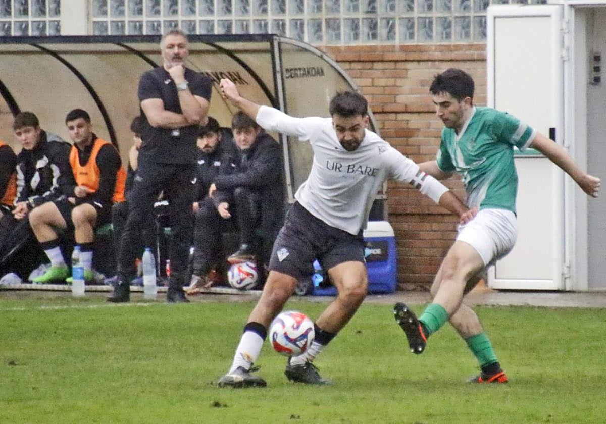 Aitor Andreano, autor del gol de la victoria en Oñati, juega el balón ante la atenta mirada del mister, Joseba Roteta y el banquillo.